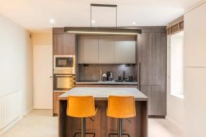 kuchnia z wyspą z dwoma pomarańczowymi stołkami barowymi w obiekcie Cocoon du vieux Lyon - Luxury apartment - Balneo w mieście Lyon