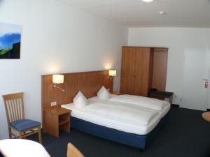 a bedroom with a large bed and a chair at Hotel Garni - Haus Gemmer in Coburg