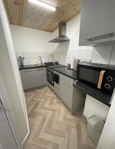 a kitchen with stainless steel appliances and a wooden floor at Unique Duplex Apartment FREE parking FREE Wi-Fi 6 minutes from Leeds city centre in Leeds