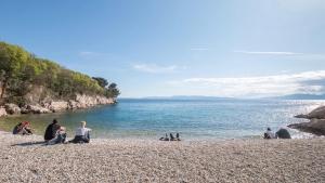 eine Gruppe von Menschen, die am Strand in der Nähe des Wassers sitzen in der Unterkunft Apartment Donna Rijeka in Rijeka