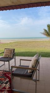 un patio con 2 sillas y vistas a la playa en شاليه على البحر UAE, Abu Dhabi, en Baţīn