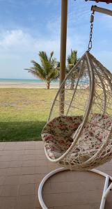 una silla mecedora en un porche con playa en شاليه على البحر UAE, Abu Dhabi, en Baţīn