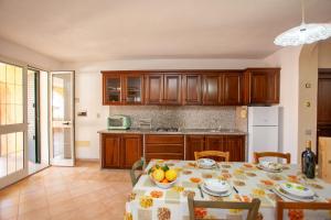 a kitchen with a table with a bowl of fruit on it at Appartamento Acacia in Cala Liberotto +14 photos
