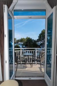 a glass door leading to a balcony with a table and chairs at Hotel Bor in Krk