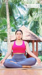 a woman sitting in a yoga pose in front of palm trees at Tropical Cradle @ River Dale in Kalyānpur