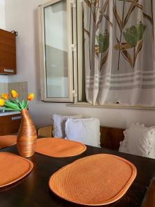 a table with orange plates and a vase on it at Casa Gaia in Avola
