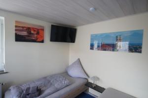 uma sala de estar com um sofá e duas fotografias na parede em Pension Obstgarten em Laupheim