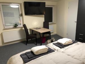 a room with two beds and a table with a tableablish at Pension Obstgarten in Laupheim
