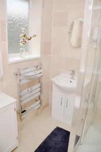 Baño blanco con lavabo y espejo en 33SM Dreams Unlimited Serviced Accommodation- Staines - Heathrow, en Stanwell