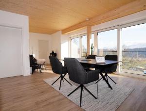 comedor con mesa, sillas y ventanas en Modernes Ferienhaus mit Panoramablick en Rosegg