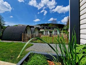 un jardin avec une maison en arrière-plan dans l'établissement Tiny rooms @ camping val d'Or, à Enscherange
