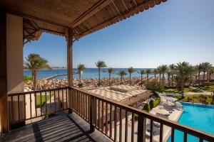 een balkon met uitzicht op het zwembad en het strand bij Jaz Makadina in Hurghada