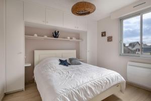 - une chambre avec un lit blanc et une fenêtre dans l'établissement Appartement moderne a 250 m de la mer, au Pouliguen