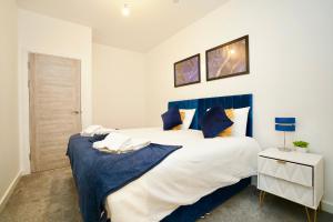 a bedroom with a large white bed with blue accents at Apartment by DH ApartHotels in Peterborough