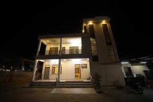 a small white house at night with lights at The Sky Comfort Shiv Ashray Resort in Nāthdwāra