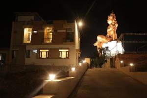 a statue of a woman standing next to a building at night at The Sky Comfort Shiv Ashray Resort in Nāthdwāra