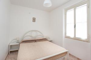 een bed in een witte kamer met 2 ramen bij Casa con giardino in Posada