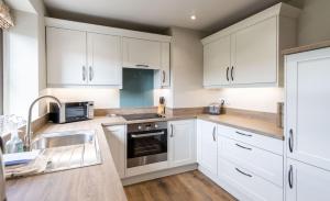 a kitchen with white cabinets and a sink at Chapel Beck, Sebergham, Nr Caldbeck in Sebergham