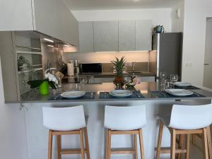 a kitchen with a counter with four white bar stools at L'écrin des Oliviers in Grasse