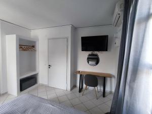 1 dormitorio con escritorio y TV en la pared en Sogni d'oro, en Poros