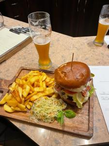 a tray with a hamburger and french fries and a glass of beer at Zajazd Reczyn - Nowy Reczyn 16 