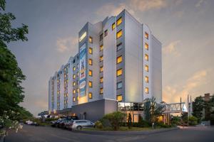 a tall white building with cars parked in front of it at Select Hotel Rüsselsheim in Rüsselsheim