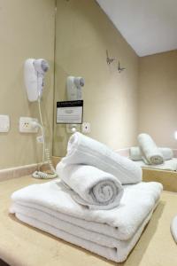 Camberland Resort & Spa Ramallo في رامالو: حمام به مناشف بيضاء ومرآة