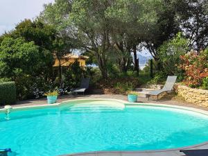 イエールにあるRez de jardin villa Presqu'ile de Giensの大きな青いスイミングプール(椅子2脚、木付)
