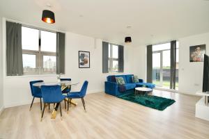ein Wohnzimmer mit einem blauen Sofa und einem Tisch in der Unterkunft Large Balcony Apartment with City View by DH ApartHotels in Peterborough