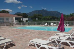 une piscine avec des chaises longues et un parasol dans l'établissement Résidence A NUCIOLA Les pieds dans l'eau Cervione Hte CORSE, à Cervione