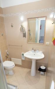 ein Badezimmer mit einem Waschbecken, einem WC und einem Spiegel in der Unterkunft Tarchon Luxury B&B in Tarquinia