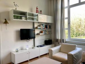 - un salon avec une télévision et une chaise dans l'établissement Residenz am Rosengarten 16, à Wangerooge