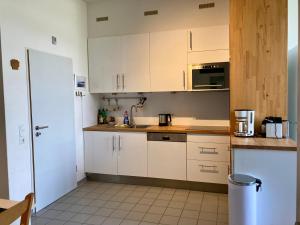 Elle comprend une petite cuisine avec des placards blancs et un réfrigérateur. dans l'établissement Residenz am Rosengarten 16, à Wangerooge