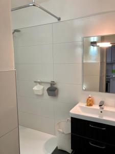 ein Bad mit einem Waschbecken und einer Dusche mit einem Spiegel in der Unterkunft Haus Seeluft Whg 11 in Wangerooge