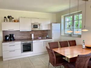 a kitchen with white cabinets and a wooden table at Ferienhaus Grodenblick Sanddorn Whg 3 in Wangerooge