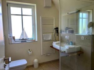a bathroom with a shower and a sink and a mirror at Ferienhaus Grodenblick Sanddorn Whg 3 in Wangerooge +16 photos