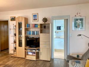 ein Wohnzimmer mit einem TV und einem Bücherregal in der Unterkunft Haus Stortebeker Whg 4 in Wangerooge