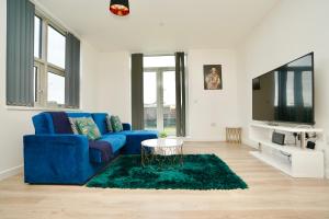 uma sala de estar com um sofá azul e uma televisão em Large Balcony Apartment with City View by DH ApartHotels em Peterborough