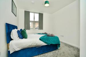 a bedroom with a bed with a blue headboard and a window at Large Balcony Apartment with City View by DH ApartHotels in Peterborough