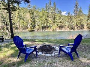 two blue chairs and a fire pit next to a lake at Jack's Cabin by NW Comfy Cabins in Leavenworth
