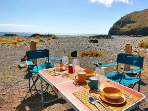 una mesa y sillas en una playa con el océano en Furgoneta Camper La Gomera 1 en San Sebastián de la Gomera