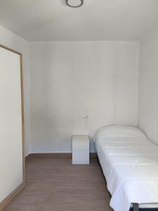 a white bedroom with a bed and a night stand at El barrio in Medina Sidonia
