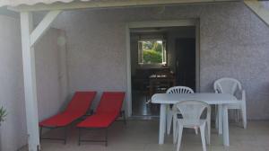 une table et des chaises avec une table blanche et des sièges rouges dans l'établissement Résidence A NUCIOLA Les pieds dans l'eau Cervione Hte CORSE, à Cervione