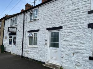un edificio de ladrillo blanco con una puerta y ventanas blancas en 3 Bedroom Cottage Sleeps 5 village location en Scarborough