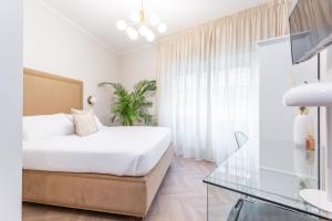 a white bedroom with a bed and a glass table at Daplace - Gran Torino Suites in Rome