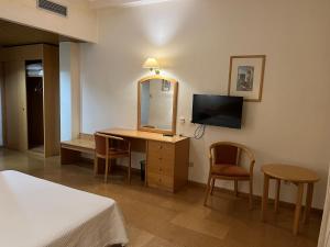 a bedroom with a desk with a mirror and a tv at Grande Hotel Dom Dinis in Mirandela