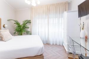 a bedroom with a white bed and a plant at Daplace - Gran Torino Suites in Rome