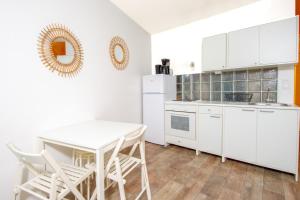 アンティーブにあるEden Residenceの白いキャビネット、テーブルと椅子付きのキッチンが備わります。