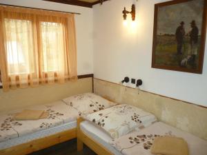 two twin beds in a room with a picture on the wall at Vincellér Vendégház 