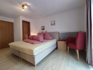 ein Schlafzimmer mit einem Bett und einem roten Stuhl in der Unterkunft Appartements Pfausler in Oetz